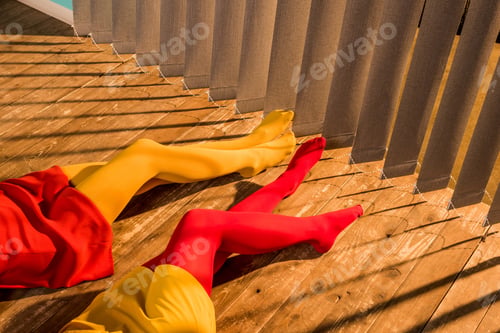 Preview: cropped image of girls in colorful tights and dresses lying on floor near jalousie
