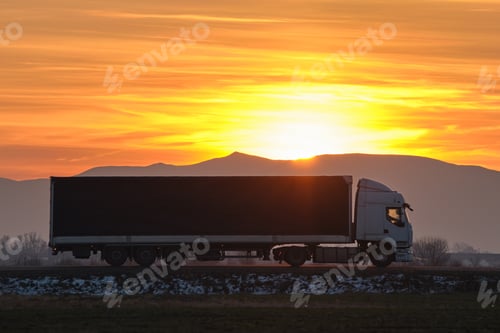 Preview: Semi-truck with cargo trailer driving on highway hauling goods in evening.