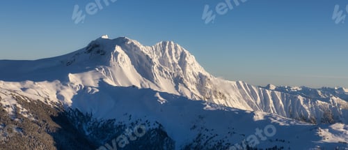 Preview: Aerial View of Canadian Mountain covered in snow during sunny winter season