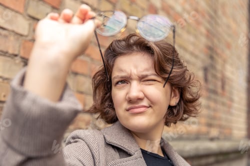 Preview: Portrait of a beautiful young woman holding glasses in her hand. Close up.