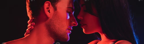 Preview: side view of young woman hugging neck of sexy man in red lighting isolated on black, banner