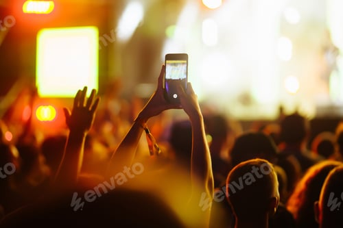 Preview: Hand with a phone records live music festival. People taking photographs with smart phone.