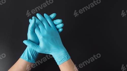 Preview: Two hand with blue latex gloves on black background.