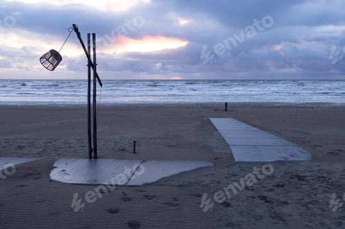 Preview: A lonely lantern on a wooden pole on a deserted sandy beach of the North Sea