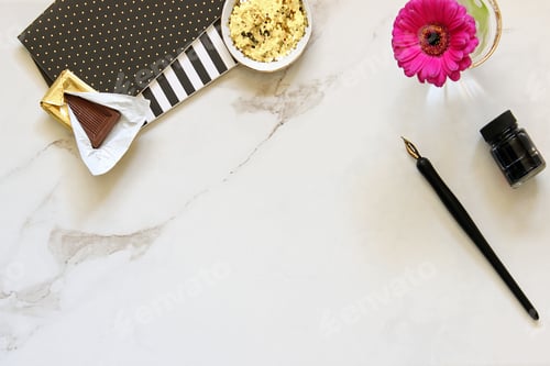 Preview: Marble desktop with office supplies, flower, chocolate and glitter. Copy space.