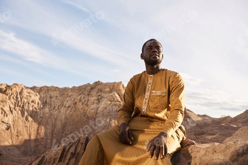 Preview: African American Man in Long Kaftan Sitting Sand Dune