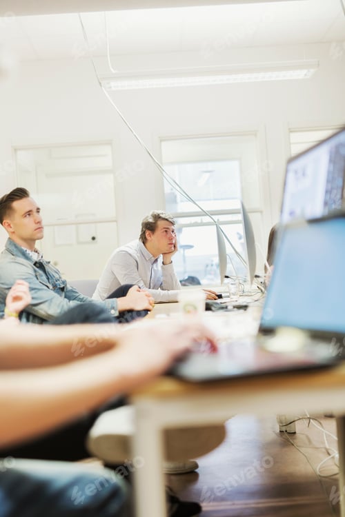 Preview: Media students looking away while sitting at computer desk in classroom