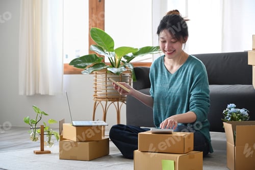 Preview: Happy asian woman online seller sitting in modern home office and preparing parcel.