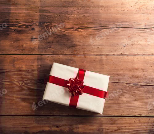 Preview: Wrapped Gift with Red Ribbon on Wooden Table