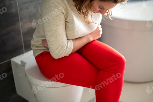 Preview: Woman sitting on the toilet with a head ache and cramps from her monthly menstruation period