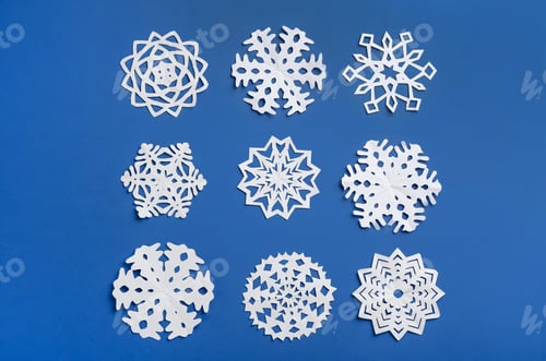 Preview: Many paper snowflakes on blue background, flat lay