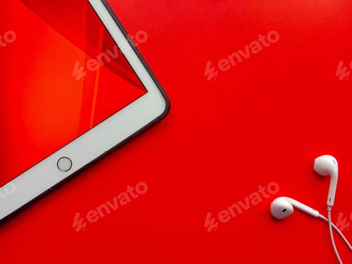 Preview: Digital tablet and headphones on red background