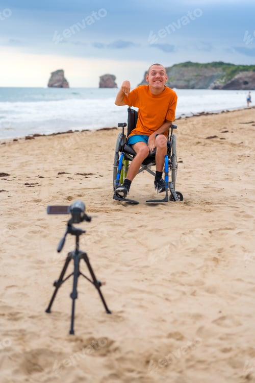 Preview: Portrait of a disabled person in a wheelchair on the beach recording a video