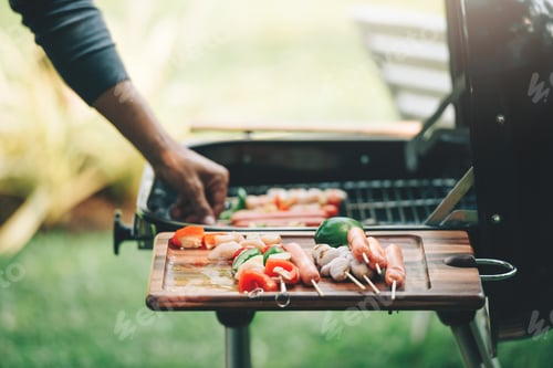 Preview: Close up photo of men cooking barbecues at backyard.