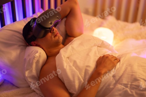 Preview: Trendy man uses VR headset at bedtime for interactive shopping, gaming, and mindfulness practice.