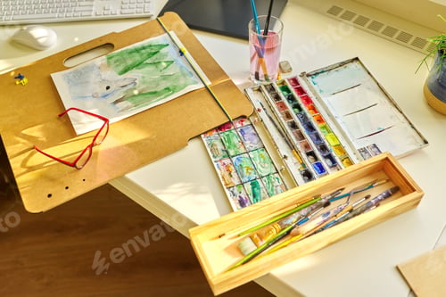 Preview: Watercolor drawing, glasses, watercolors in a box, brushes on the table, nobody