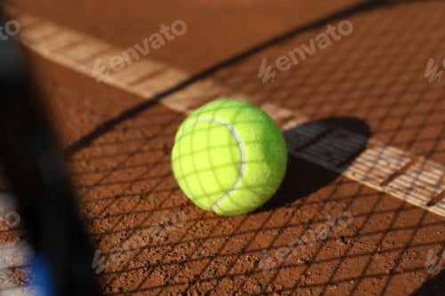 Preview: Bright yellow tennis ball on clay court