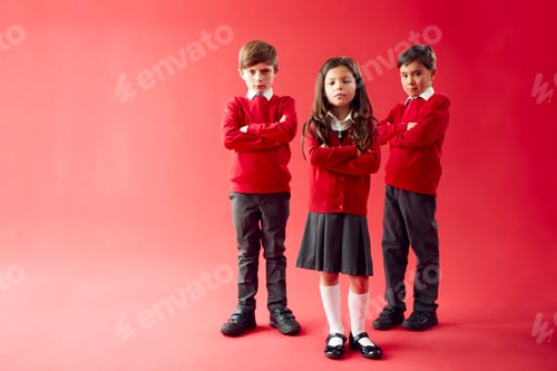 Preview: Group Of Elementary School Pupils Wearing Uniform Folding Arms Against Red Studio Background