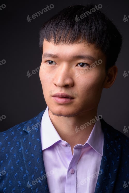 Preview: Portrait of young Chinese businessman against gray background