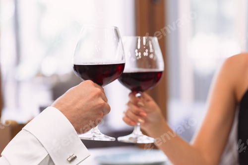 Preview: Couple toasting with red wine glasses in a cozy restaurant setting