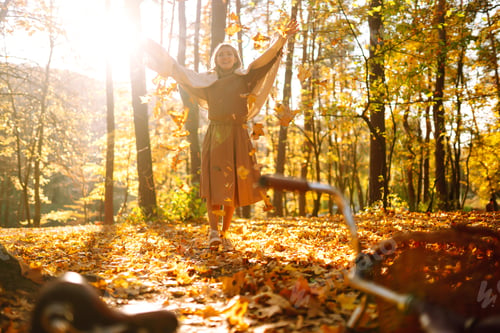 Preview: Happy young woman having fun with leaves in autumn park.