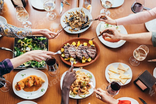 Preview: zenithal shot of an interracial group of friends poking food with their forks