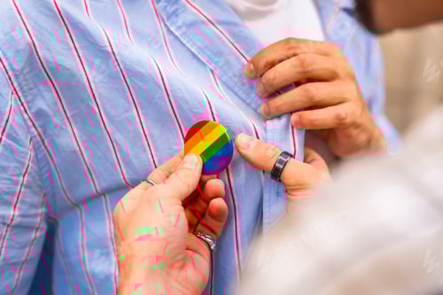 Preview: Couple attaching rainbow pride flag pin to shirt