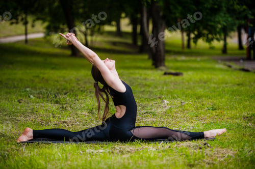 Preview: Beautiful young woman doing relaxing and stretching exercises in the park.