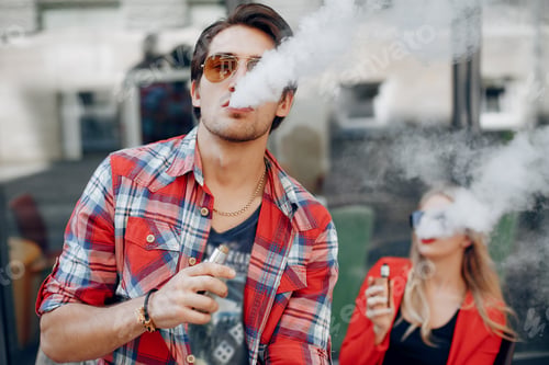 Preview: Stylish young couple with vape in a city