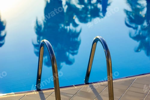Preview: Tropical empty pool with a steel ladder to enter the water. Social distancing, cancellation of trip