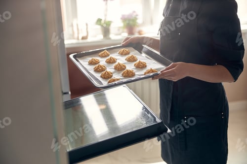 Preview: Professional confident woman is preparing custard cakes at light modern kitchen at home