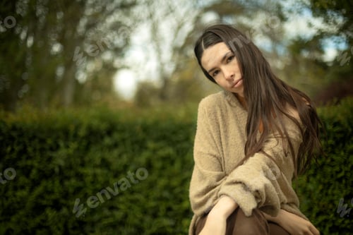 Preview: Outdoor portrait of young caucasian model woman sitting looking at camera. photo with copy space