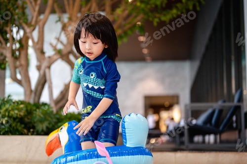 Preview: Little boy in swimming pool on funny inflatable hornbill float ring, learning how to swim.Summer