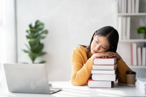 Preview: Asian college student relaxing after reading and doing homework for the project while sitting in a c