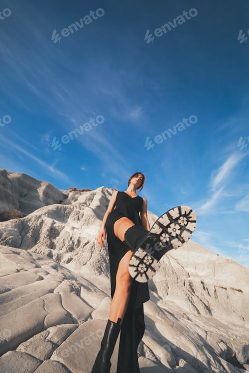 Preview: Beautiful model with black dress and boots in the mountains