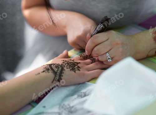 Preview: Artist applying henna tattoo on women hands