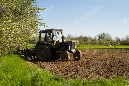 Preview: The tractor drives across the field and cultivates the land.