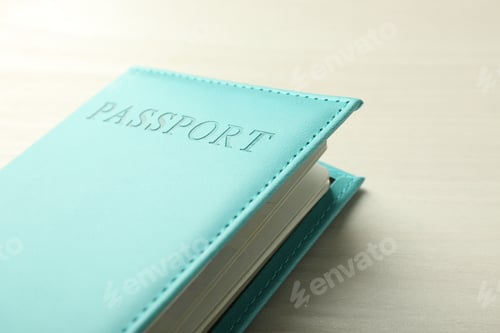 Preview: Passport in bright turquoise cover on white wooden table, closeup