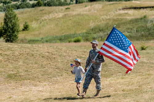 Preview: military man and happy patriotic kid walking and holding american flags