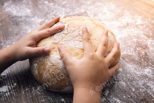 Preview: hands of a child on a loaf of rustic bread