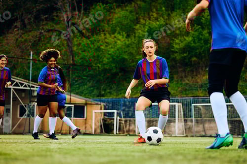 Preview: Athletic woman passing the ball during soccer training on playing field.