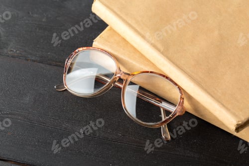 Preview: Vintage Eyeglasses Resting on Books on Black Background