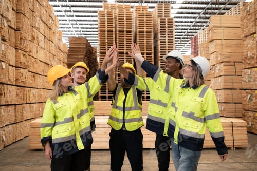 Preview: Portrait of happy workers giving high five at warehouse.