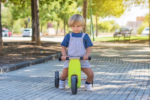 Preview: Blond boy playing outdoors with small balance bike