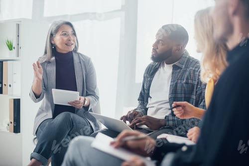 Preview: selective focus of multicultural colleagues with gadgets sitting and talking in office