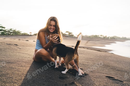 Vista previa: Mujer alegre en traje de baño jugando con un lindo Beagle en la playa