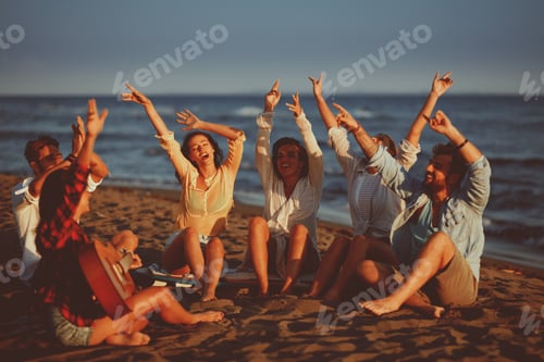 Preview: Happy friends sitting on the beach singing and playing guitar during the sunset