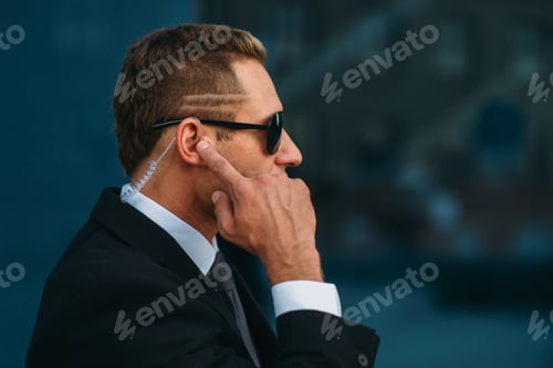 Man in Suit and Sunglasses Listens