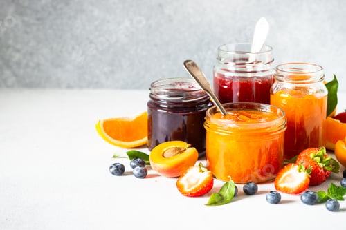 Preview: Homemade jam in glass jars at white table.