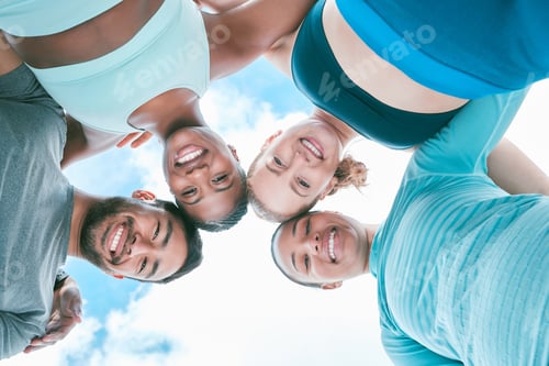 Preview: Portrait of a diverse group of happy sporty people from below joining their heads together in a hud